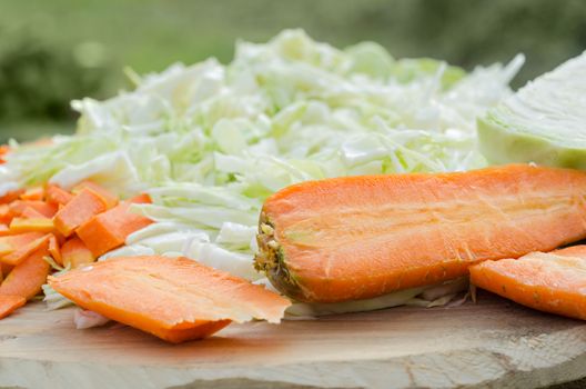 Sliced cabbage and carrots on a rough Board. Ingredients for cooking outdoors