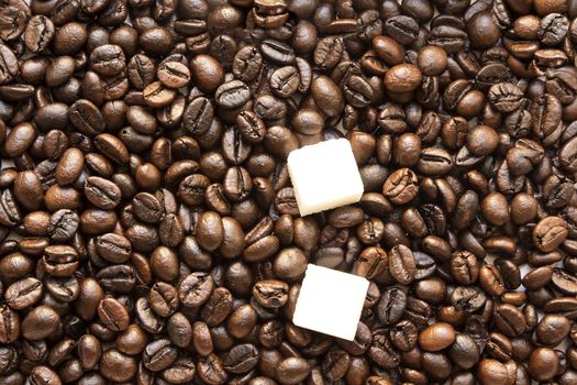 pieces of white sugar in coffee roasted beans Brown background