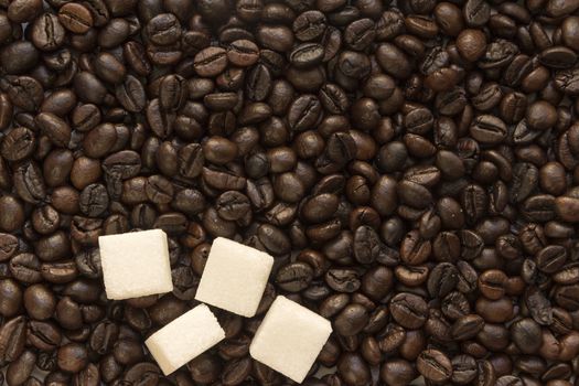 pieces of white sugar in coffee roasted beans Brown background