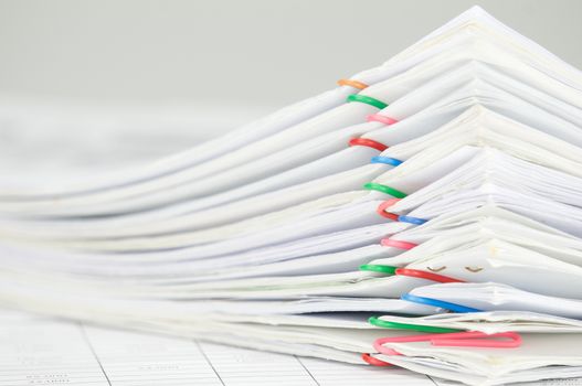 Pile overload document of report with colorful paperclip on finance account with white background.