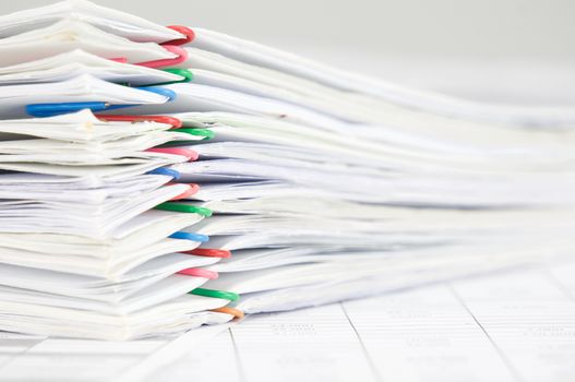 Pile overload paperwork of report with colorful paperclip on finance account with white background.