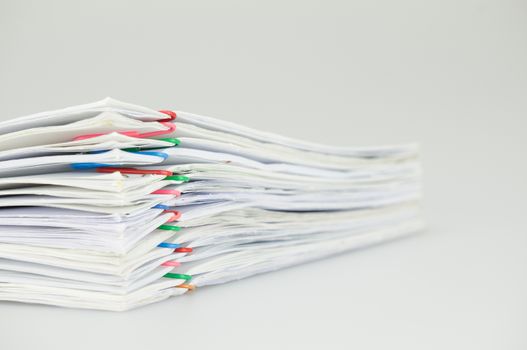 Pile overload paperwork of report with colorful paperclip place on white background.