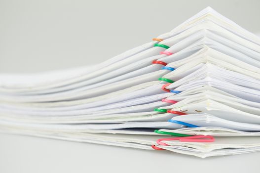 Pile overload document of report with colorful paperclip place on white background.