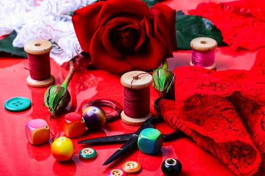 Thread,bead,button, and rose on bright red background