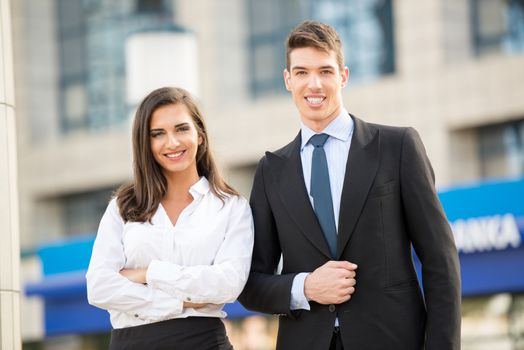 Young business couple standing in front of their office building satisfied with their business success.