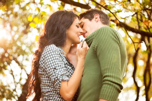 Young heterosexual couple in love in the park, photographed at the moment while the girl pulls the boy to kiss him.