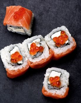 Delicious Sushi with Smoked Sliced Salmon and Gourmet Red Caviar closeup on Stone Plate. Top View