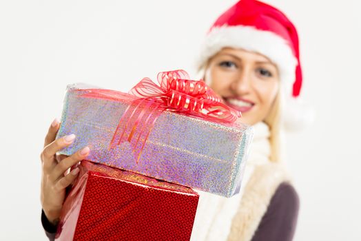 Close-up beautifully wrapped gifts with a decorative bow, holding a young pretty blonde girl with Santa's hat. The girl is out of focus.