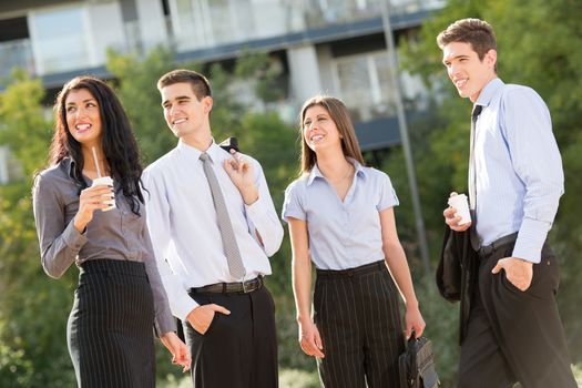 Group of young business people, elegantly dressed, on the coffee break, standing in a park near their company enjoying the sunny day.