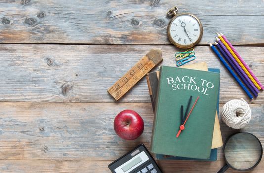 Book with clock hands with stationery accessories on a wooden and space for text 