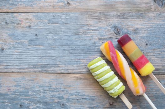 Three frozen ice lollies on a wooden background