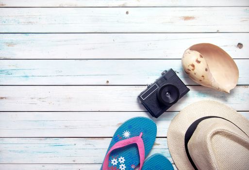 Vacation items, inluding sunglasses, and camera, on white wooden planks with space