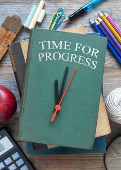 Education schooling stationery items on a wooden table with time for progress clock book cover 