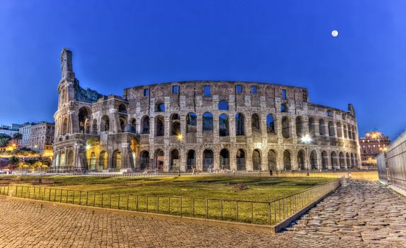 Coliseum behind rocks by night, Roma, Italy