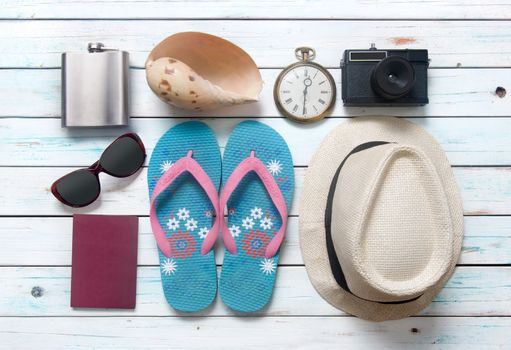 Vacation items, inluding sunglasses, and camera, on white wooden planks