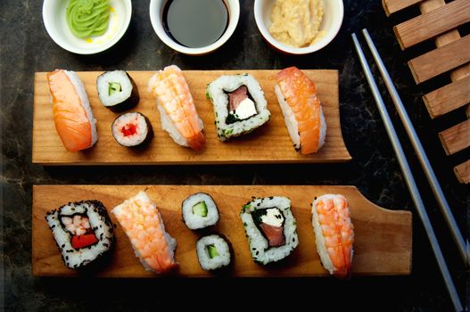 Selection of sushi including prawns, salmon and vegetables with rice on serving blocks