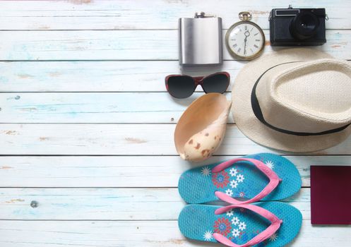 Vacation items, inluding sunglasses, and camera, over a wooden background with space