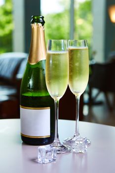 Two elegant champagne glasses on the background of green bottle. Festive still life.