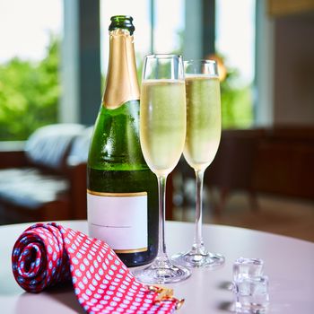 Two elegant champagne glasses on the background of green bottle. Festive still life.