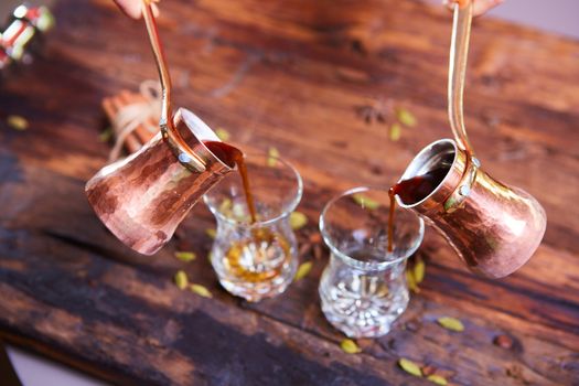 To pour arabic coffee in cups on wooden background. Glass cups