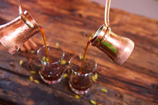 To pour arabic coffee in cups on wooden background. Glass cups