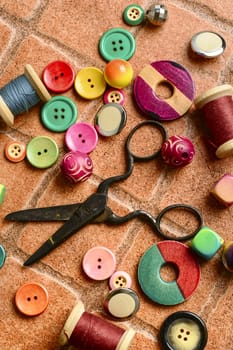 Sewing kit from buttons,beads and scissors on the brick background