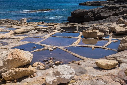 Holes in rocks at the seaside of the Mediterranean sea, for evaporation the water and getting sea salt. City Marsaskala, island Malta.