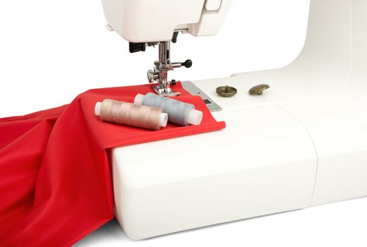 Machine sews at red fabric isolated on white background, closeup