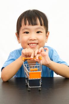 Chinese little girl pushing a toy shopping cart in plain white isolated background.