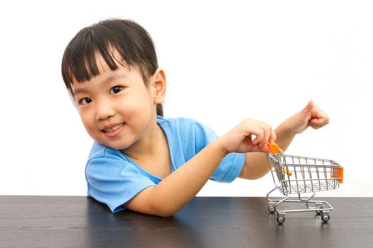 Chinese little girl pushing a toy shopping cart in plain white isolated background.