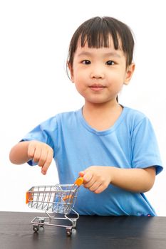Chinese little girl pushing a toy shopping cart in plain white isolated background.