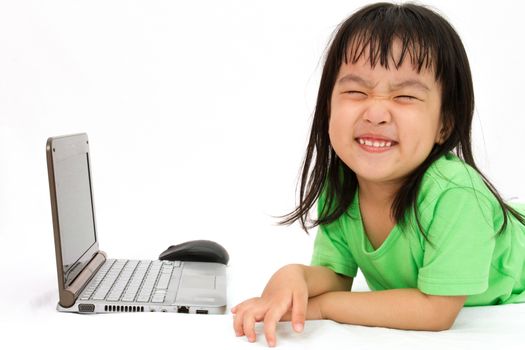 Chinese little girl lying down with laptop in plain white isolated background.