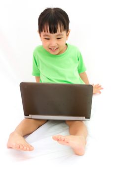 Chinese little girl sitting on floor with laptop in plain isolated white background.