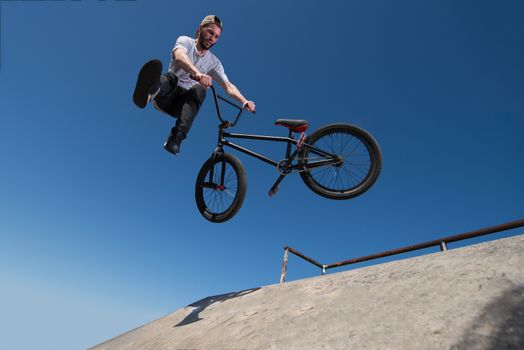 Bmx rider performing a tail whip at a quarter pipe ramp on a skatepark.