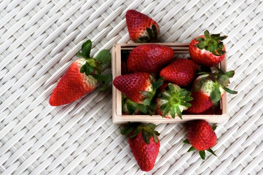 Heap of Fresh Ripe Strawberries in Wooden Tray closeup on Wicker background. Top View