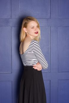 Beautiful blonde in a shirt-vest near a blue wall