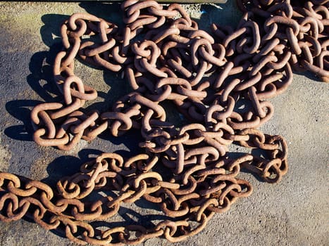 Old rusty metal iron chain on the ground in a port  