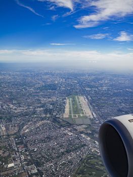 Aerial photo of Bangkok, Thailand, with Don Mueang International Airport, the city’s budget airline airport, in the foreground and Bangkok downtown in the background. Notice the 9-hole golf course between the runways at the airport.