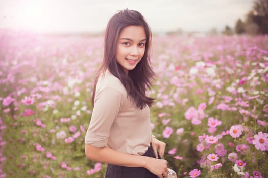 Beautiful asian women smiling in pink cosmos flower field .