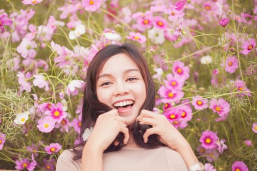 Beautiful asian women smiling in pink cosmos flower field .