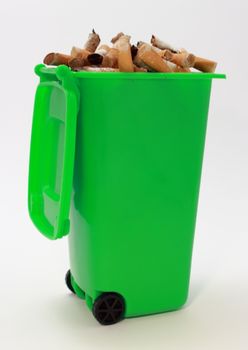 Used cigarette butts in green waste bin on white background