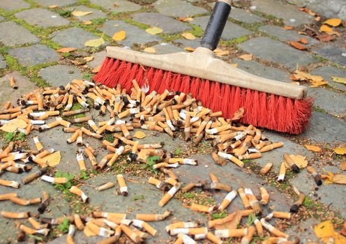 Sweeping a lot of cigarette butts from stone road