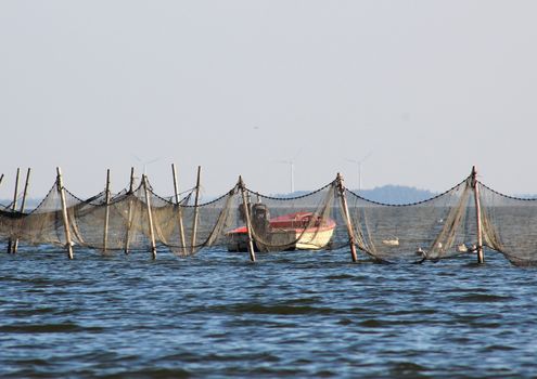 Small boat near offshore fishing net and traps