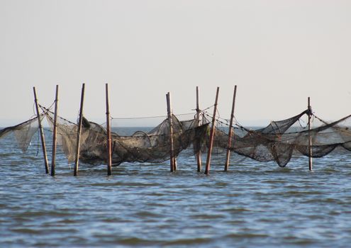 Isolated fishing traps hanging between wooden poles offshore