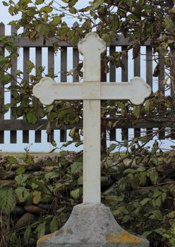 Old metal cross on top of headstone at graveyard