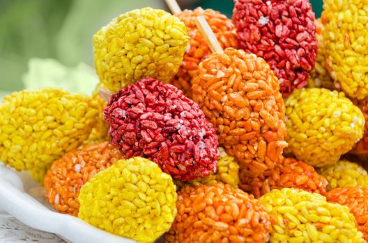 Sweet puffed rice on a stick, multi-colored market tray