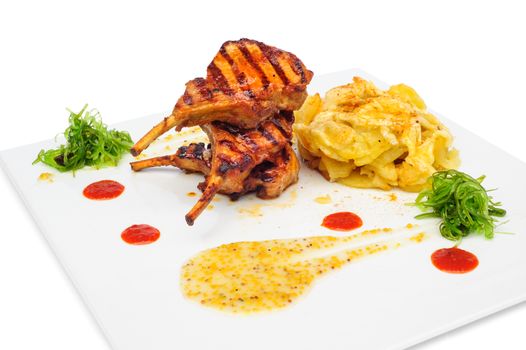 Grilled rabbit legs on big plate with fried potato and sea weeds