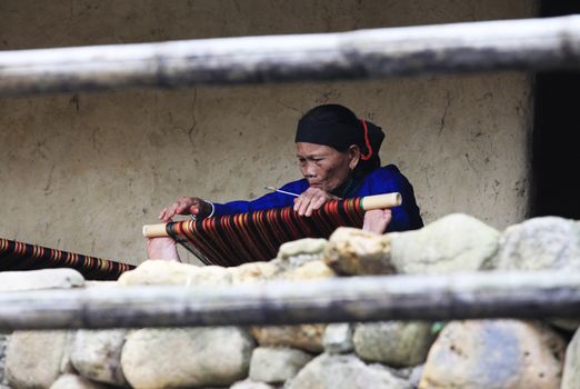 Hainan, China - April 7, 2012: Mature woman works on an ancient loom in Hainan. China
