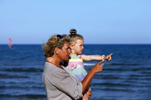 Grandmother with a little granddaughter on the beach