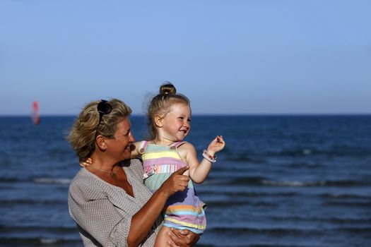 Grandmother with a little granddaughter on the beach
